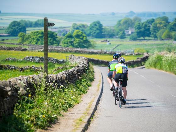 Two cyclists cycling along a country road